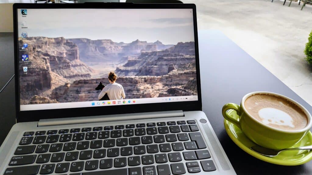 筆者のLenovo IdeaPad Slim 3 Gen 10 14型  (AMD)をカフェで使っている写真。飲み物と一緒に置けるジャストサイズがうれしい。